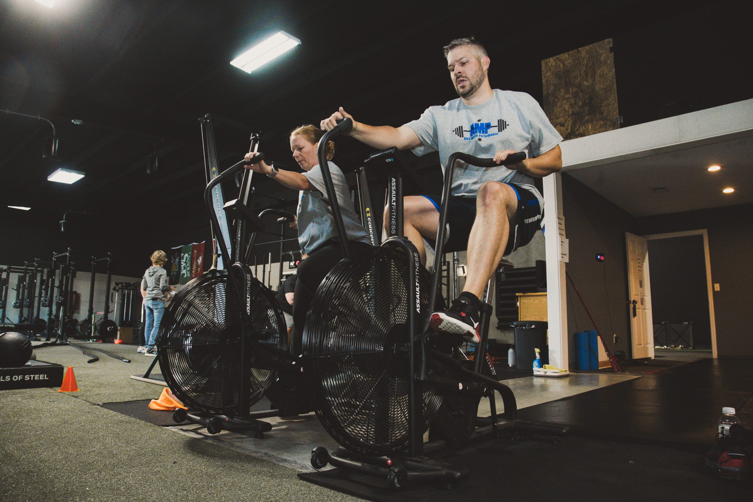 Man and woman riding exercise bikes for cardiovascular endurance and fitness training at Alex Makin Performance.