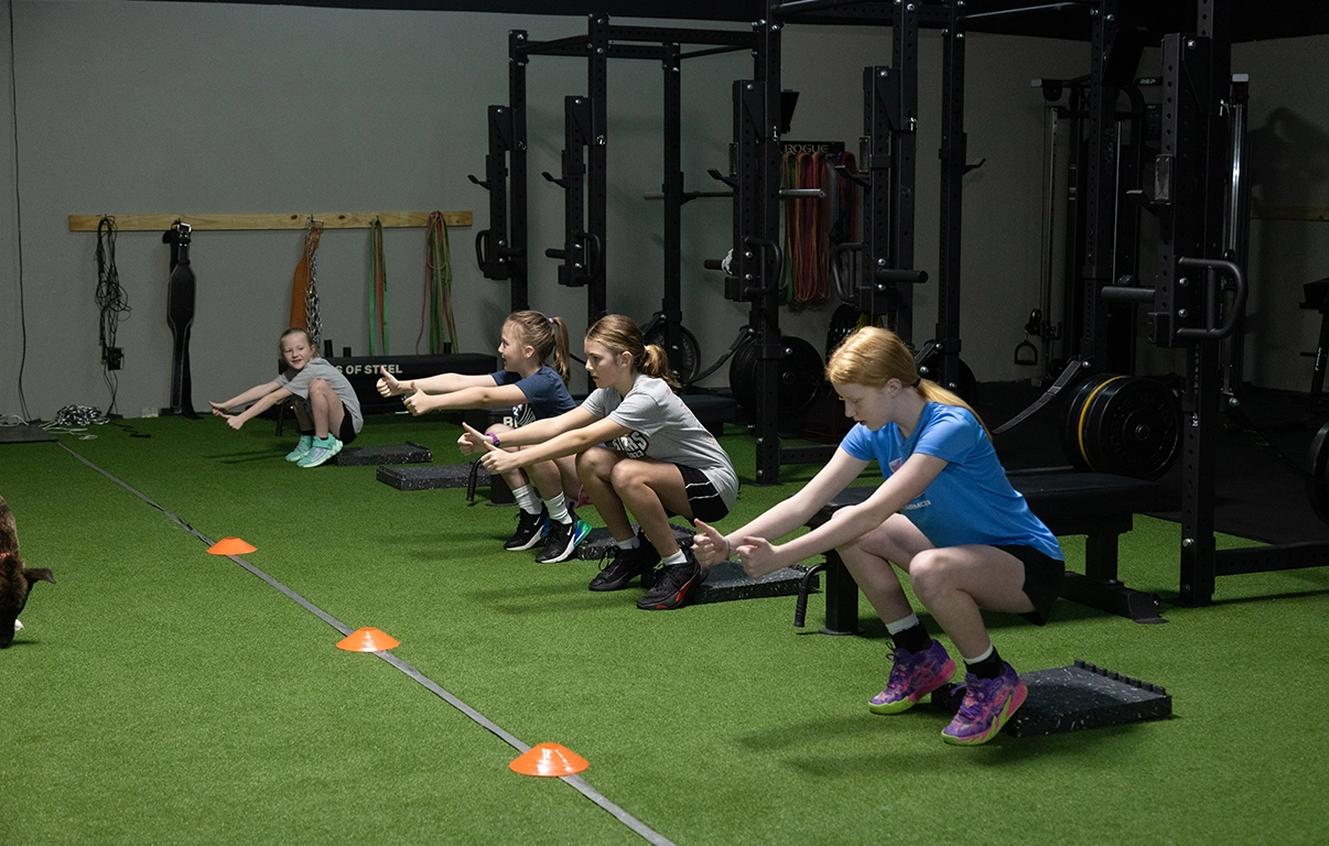 Group of young athletes performing squats at AMP youth training.