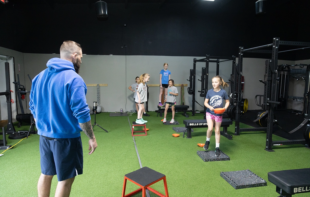 Youth athletes performing box step-ups during a fitness session at Alex Makin Performance