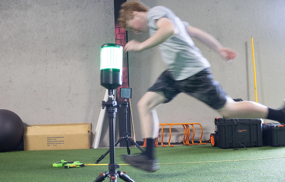 Teen athlete sprinting through smart speed timing gates at AMP's teen athletic training program.