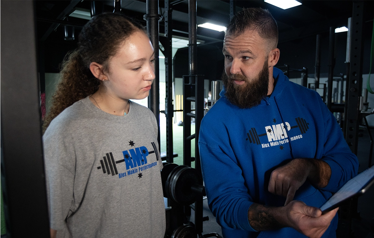 Alex Makin providing feedback to a teen athlete at AMP gym during a teen athletic training program session.