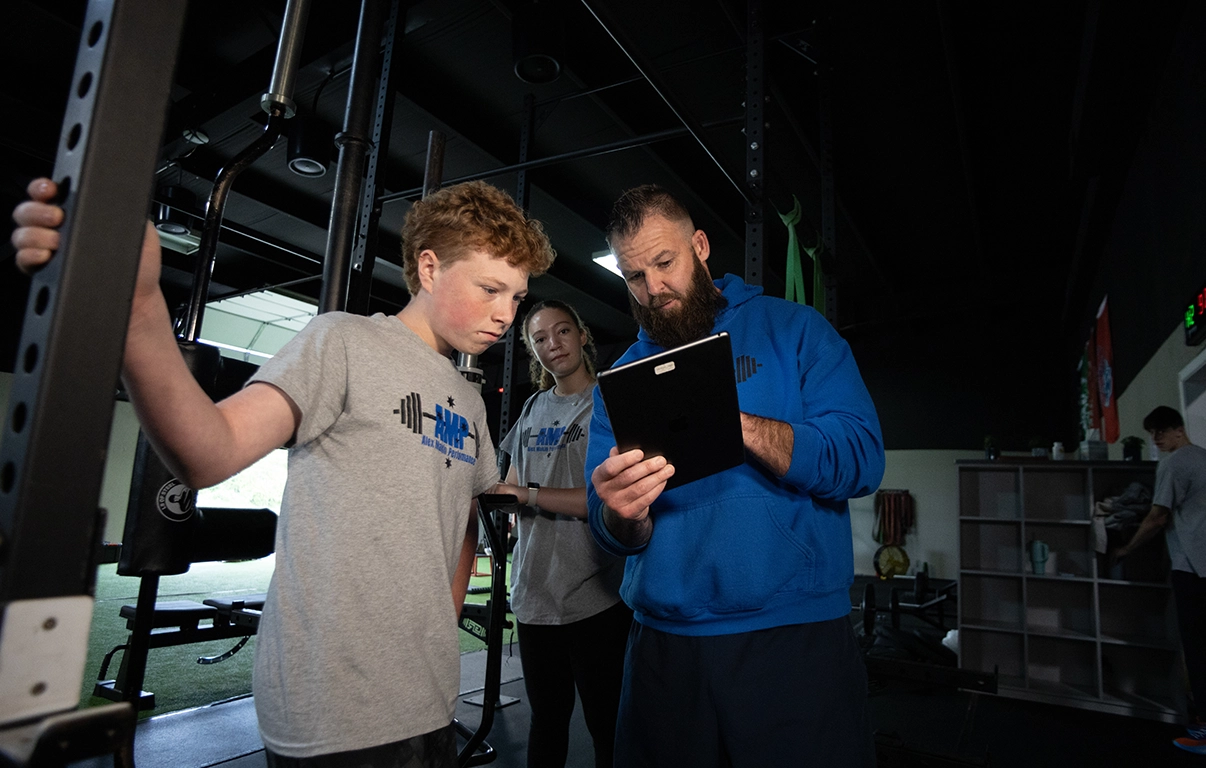 Alex Makin reviewing workout data with teen athlete at AMP during a teen athletic training session.