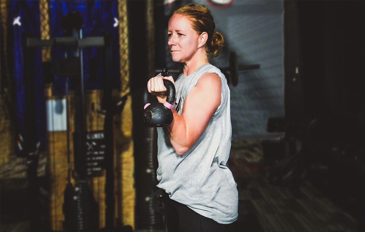 Woman lifting a kettlebell for strength training at Alex Makin Performance's adult fitness training classes.