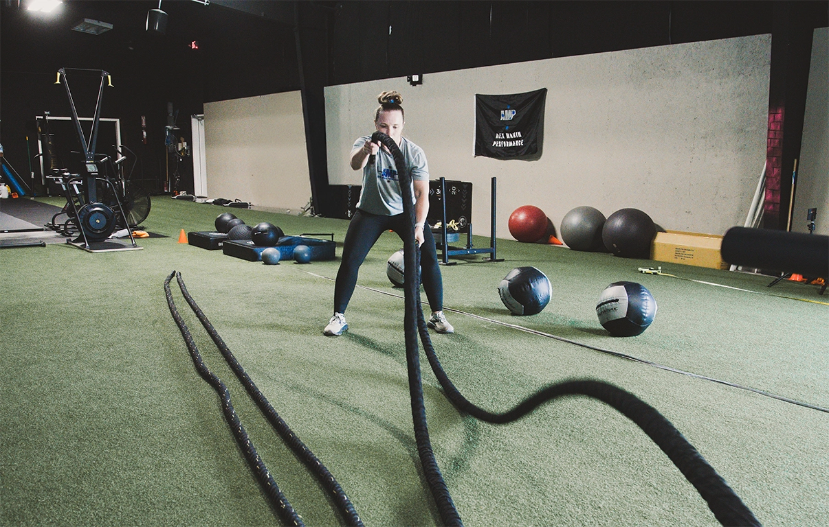 Woman performing battle rope exercises for adult fitness training, strength and endurance at Alex Makin Performance.