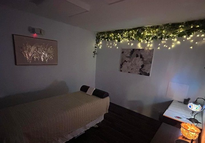 Cozy massage room with soft lighting and greenery at Alex Makin Performance's specialized sports and wellness program..